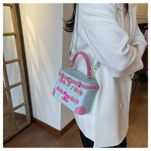 Detail of blue box bag featuring pink rabbit print and contrasting trim on white blazer