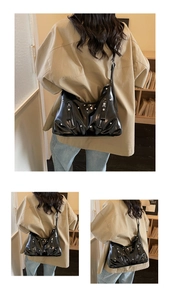 Detail der schwarzen Lackleder-Schultertasche mit silbernen Nieten und Reißverschlüssen