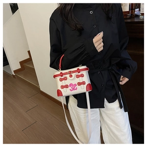Detail of white and red box bag with pink rabbit embroidery and golden buckles