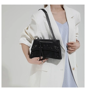 Detailed close-up of a black punk-style chain shoulder bag with metallic silver rivets