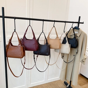 Sacs à main tissés à la main en cuir de diverses couleurs sur un présentoir moderne