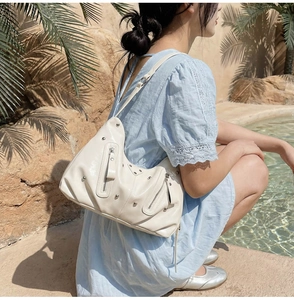 Détail du sac hobo crème avec rivets argentés et zips décoratifs sur modèle