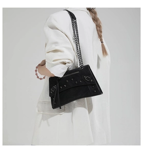Detail of black matte hourglass crossbody bag with metal rivets and chain strap