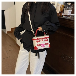Detail of a white mini box bag with red trim and a cute pink rabbit print on a model