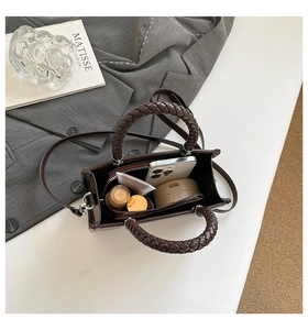 Detail view of dark brown tote bag with woven handles and interior storage capacity
