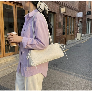 Detail of cream sequin shoulder bag with star patterns and bows in a street setting