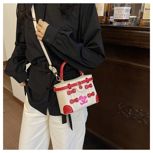 Detail of white box bag with red leather trim and cute rabbit print worn on shoulder