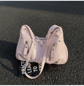 Détail du sac cabas rose clair style moto avec clous et fermetures éclair sur magazine