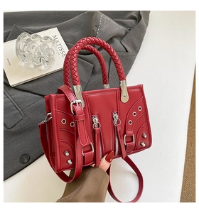 Detailed view of red motorcycle bag with silver rivets and woven leather handles