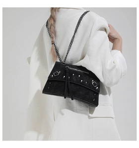 Detail of black punk motorcycle bag featuring silver studs, buckles, and heavy chain strap