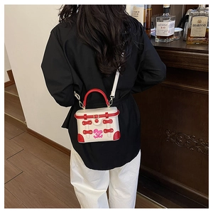 Detail of a mini box bag with red handles and cartoon bunny print worn by a model