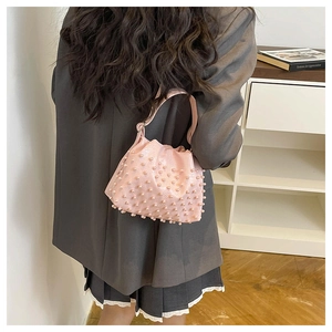 Borsa a mano rosa decorata con perle portata a spalla in un interno casa minimalista