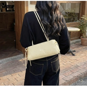 Detailed view of yellow shoulder bag with silver star patterns and knotted straps