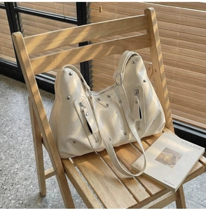 Détails macro d'un sac hobo en cuir verni blanc avec rivets et ferrures métalliques