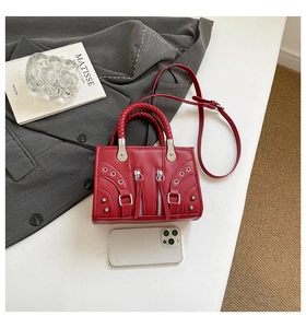 Detail of a red leather motorcycle bag with silver rivets and studs on a grey suit jacket