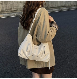 Détail du sac crème avec rivets et plaque triangulaire sur cuir synthétique texturé