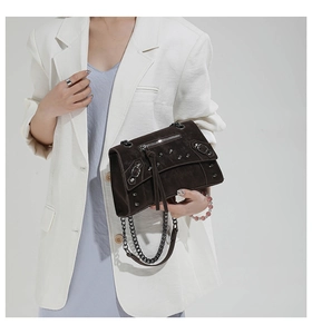 Detail of dark brown rivet motorcycle crossbody bag with tassels and silver chain strap