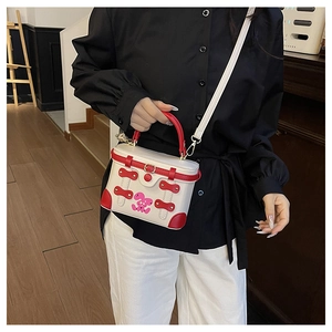 Detail showing contrast box bag with red handle, buckle and cute rabbit design