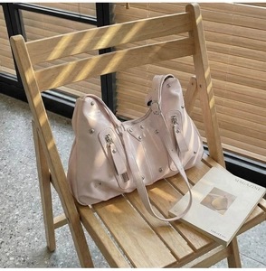 Détail du sac en cuir verni rose clair avec rivets argentés et fermetures éclair
