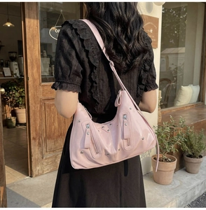 Détail d'un sac hobo rose pâle avec des clous argentés et des fermetures éclair