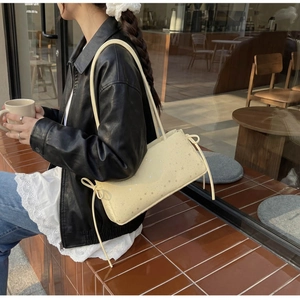Detail of cream shoulder bag with star print and side drawstring ribbons in street style