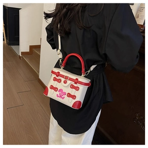 Close-up of a white and red box bag with a pink rabbit print on a model in a black suit