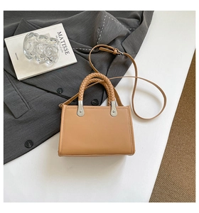 Detail of light brown tote bag with braided handle and silver metal hardware accents
