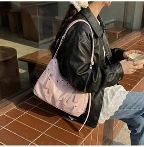Détail du sac à main rose clouté avec fermetures éclair argentées porté par un mannequin