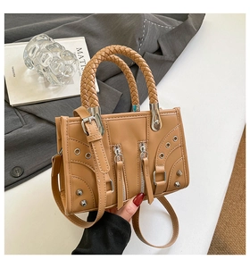 Detailed macro view of brown faux leather bag with woven handle and rivet accents