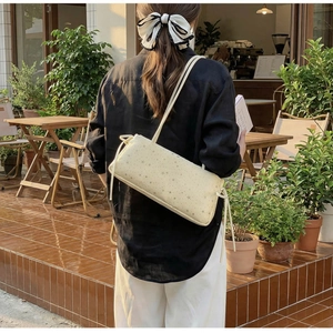 Detail of cream rectangular bag with star pattern and drawstring on a model