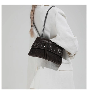 Detail of dark brown faux suede crossbody bag with metallic rivets and long fringe