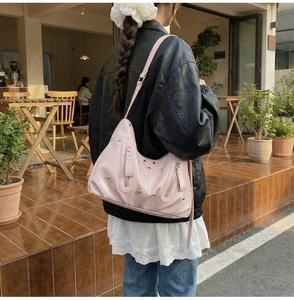 Détail du sac en similicuir rose avec rivets et fermetures éclair dans un café en plein air