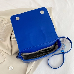 Bright blue PU leather motorcycle crossbody bag with silver magnetic snaps and textured lining