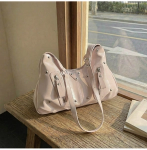 Détails du sac en cuir verni rose avec rivets argentés et fermetures éclair sur un banc