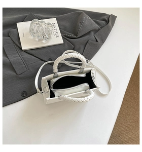 Top view of white square handbag showing woven handle and inner zip pouch detail