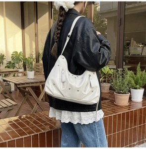 Détail du sac hobo en similicuir blanc avec clous argentés et fermeture sur la bandoulière