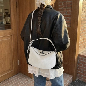 Retro dumpling crossbody bag in light grey suede with silver metal lock on a street model