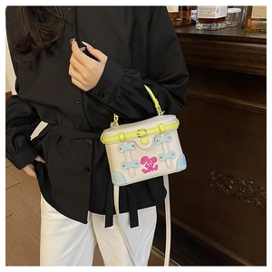 Detail of crossbody bag with neon green handle and pink cartoon rabbit illustration