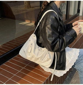 Détail du sac hobo blanc brillant avec rivets argentés et fermetures éclair métalliques
