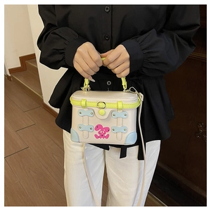Detail of contrast color mini box bag with green handles and pink cartoon rabbit pattern