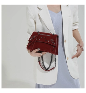 Detail of dark red punk style bag with silver rivets and metal chain strap on model