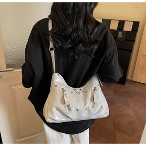 Detail der weißen Lackleder-Schultertasche mit silbernen Nieten und Reißverschlusstaschen