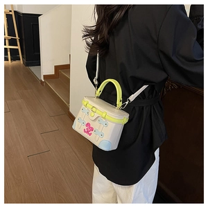 Detail showing contrast color box bag with neon green handle and cute rabbit design