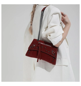 Detail of dark red oil-wax leather bag with silver rivets, fringe and chain strap
