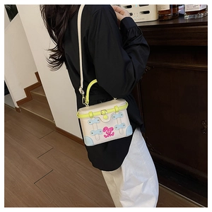 Detail view of a mini box bag with neon handles and cute rabbit pattern on a model