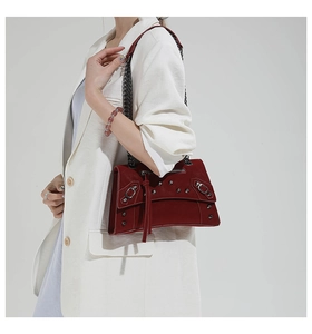 Detailed view of burgundy chain crossbody bag with silver rivets and leather tassels on model