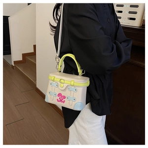 Detail of trendy box bag showing contrast neon green handle and cute pink rabbit print