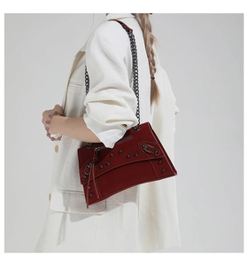 Detail of dark red motorcycle bag with black rivets and chain strap on white blazer