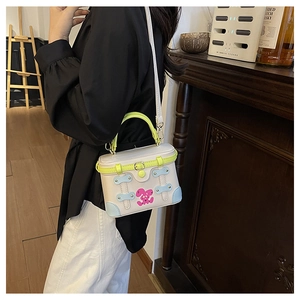 Detail of contrast color mini trunk bag featuring cartoon rabbit print and green handle