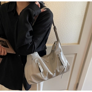Gros plan d'un sac hobo blanc cassé avec rivets argentés et plaque de logo triangulaire